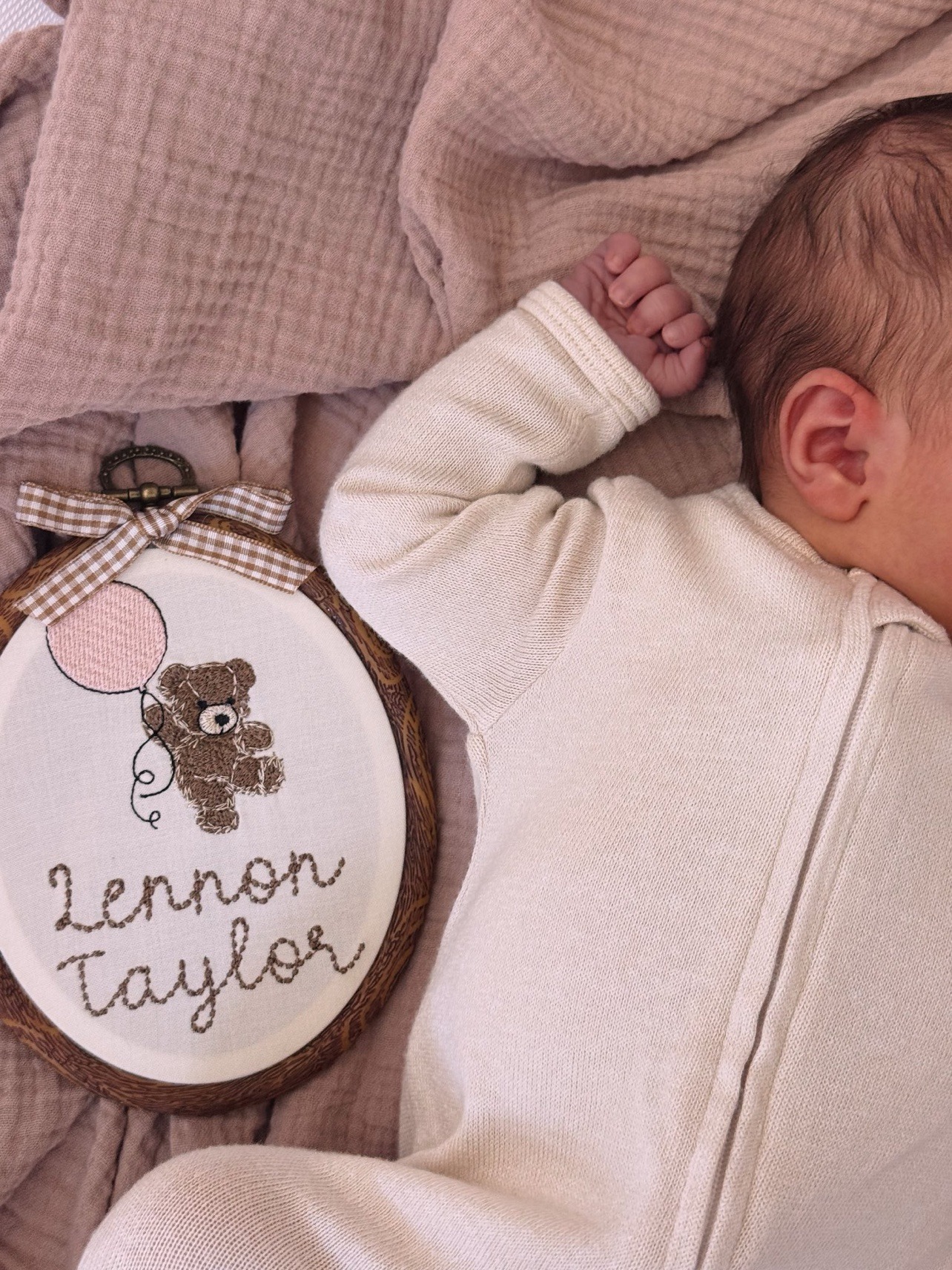 Baby announcement photo: embroidered 'Lennon Taylor' hoop beside newborn Lennon Taylor Lautner