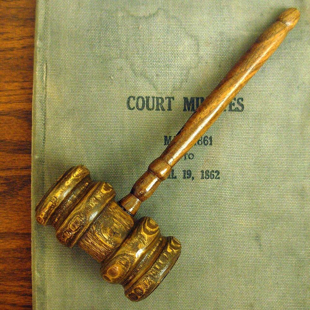 A wooden judge's gavel resting on a court minutes book