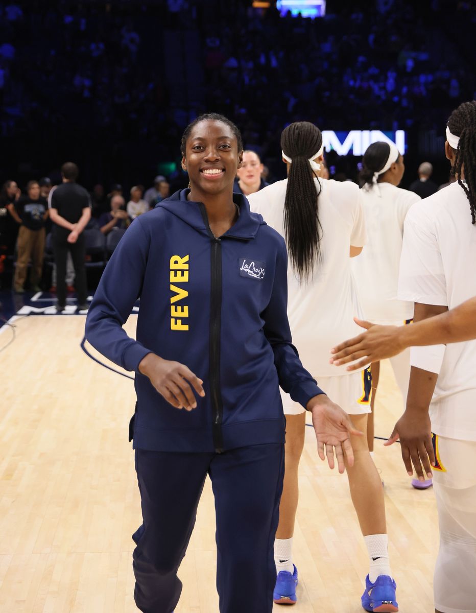 Kelsey Mitchell of the Indiana Fever smiling on the court in a blue Fever warmup