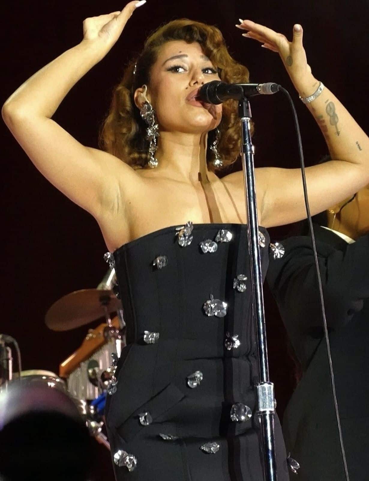 RAYE performing on stage with a microphone