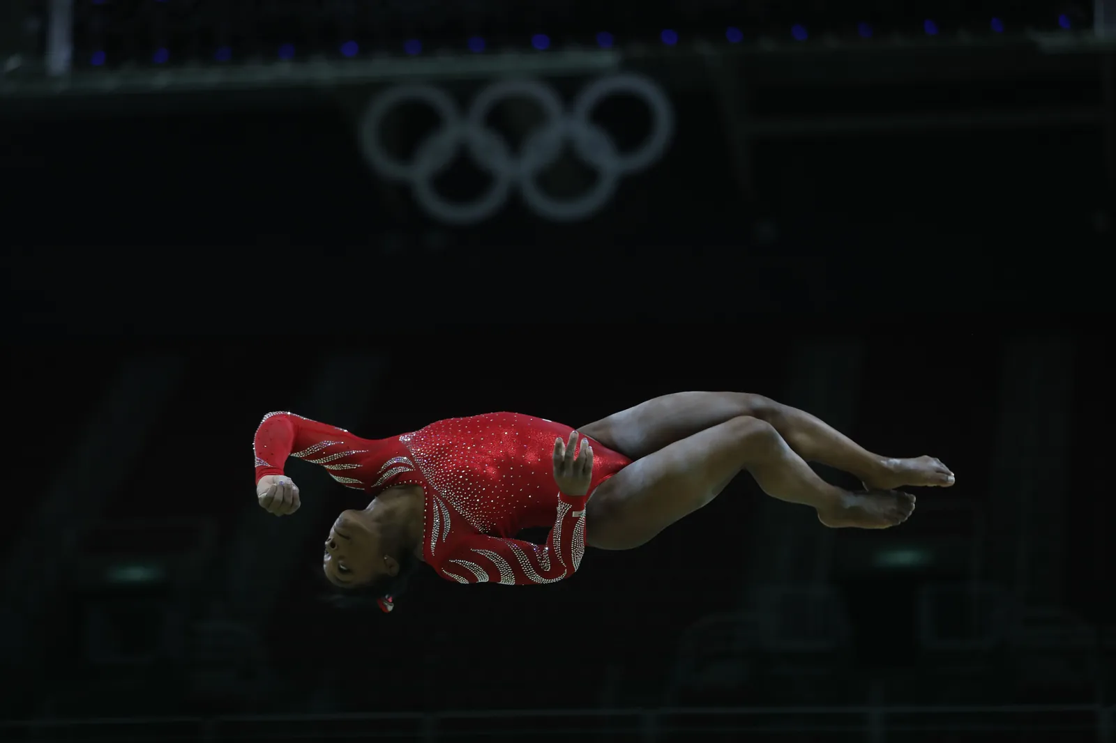 Simone Biles performs a floor exercise tumble mid-air in a red leotard at the Rio 2016 Olympics