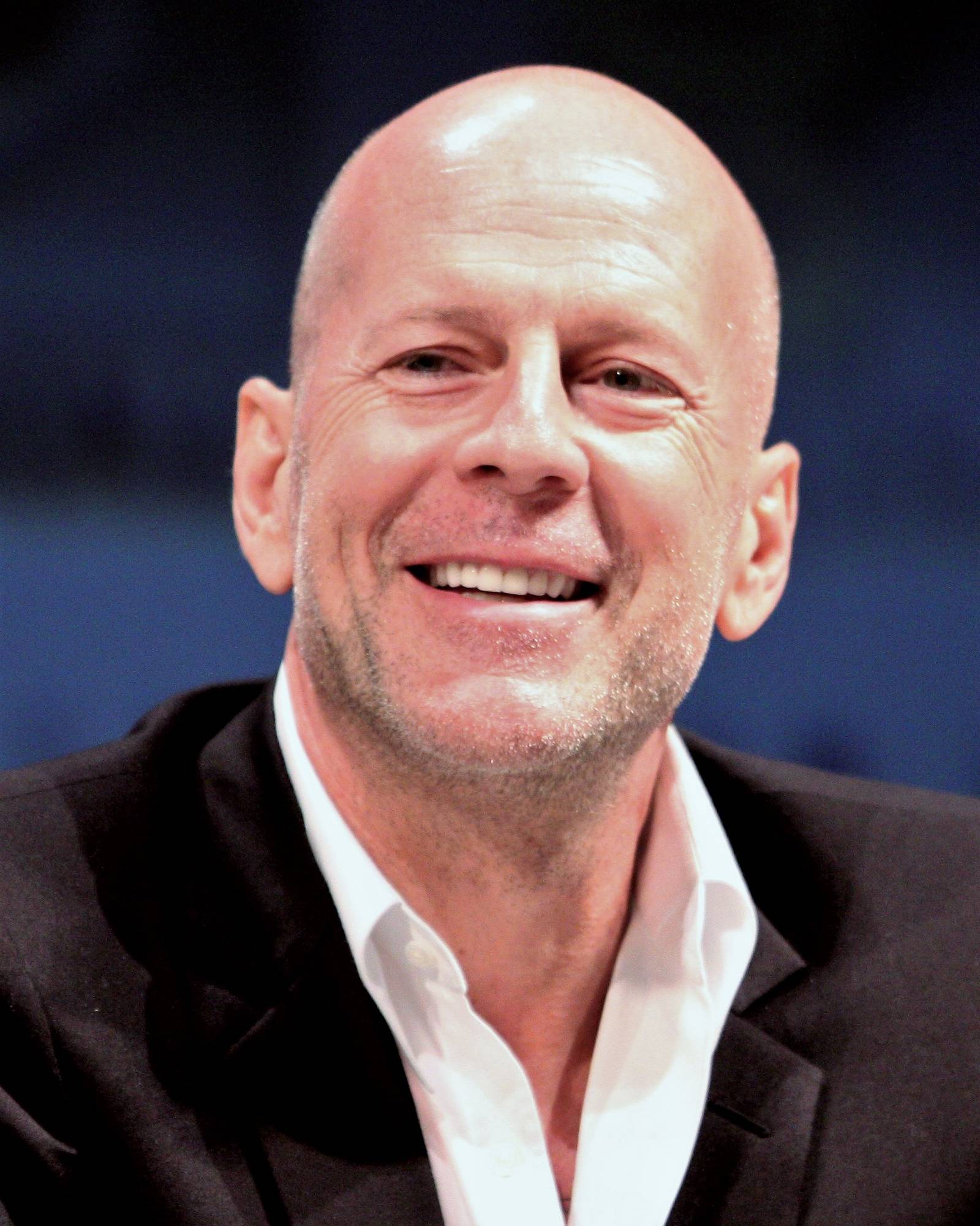Bruce Willis smiling warmly at a public event before his retirement from acting