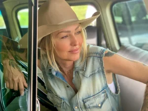 Leticia Cline wearing a cowboy hat, leaning in the window of an antique truck