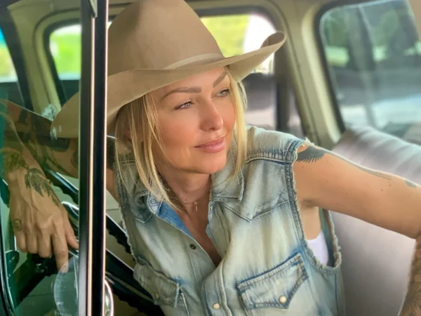 Leticia Cline wearing a cowboy hat, leaning in the window of an antique truck