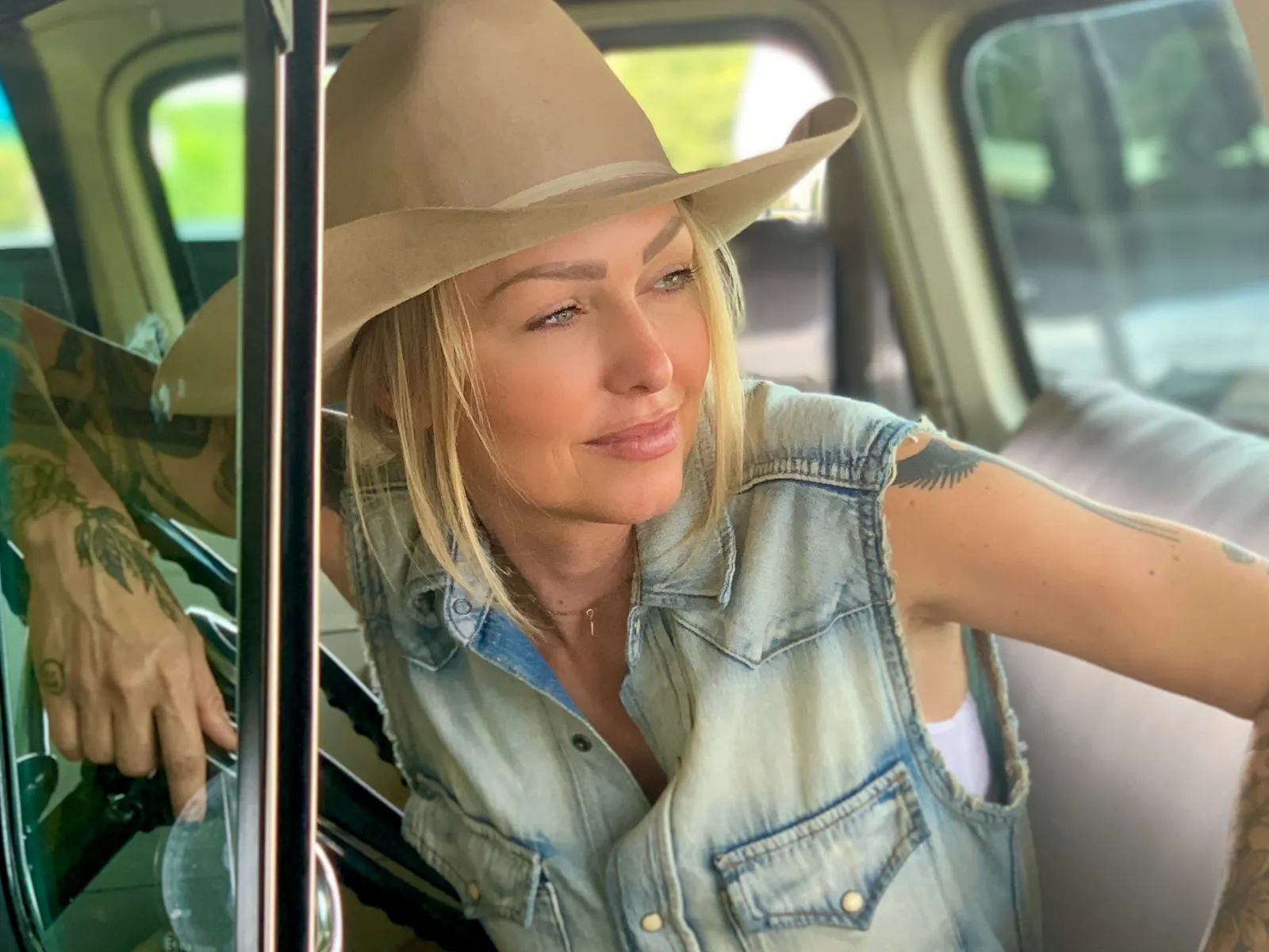 Leticia Cline wearing a cowboy hat, leaning in the window of an antique truck