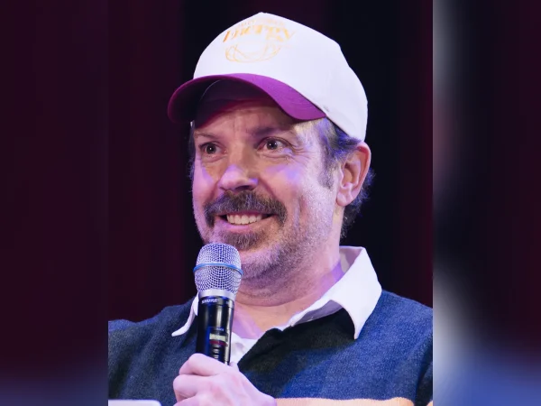 Jason Sudeikis smiling with a microphone at a 2026 event