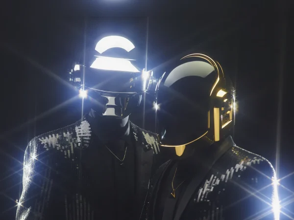 Daft Punk in their iconic silver and gold robot helmets against a black background