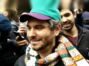 Ethan Klein smiling at a public appearance wearing a cap and scarf