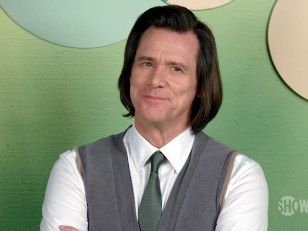 Jim Carrey smiling in a white shirt, grey vest and green tie at a 2020 media appearance