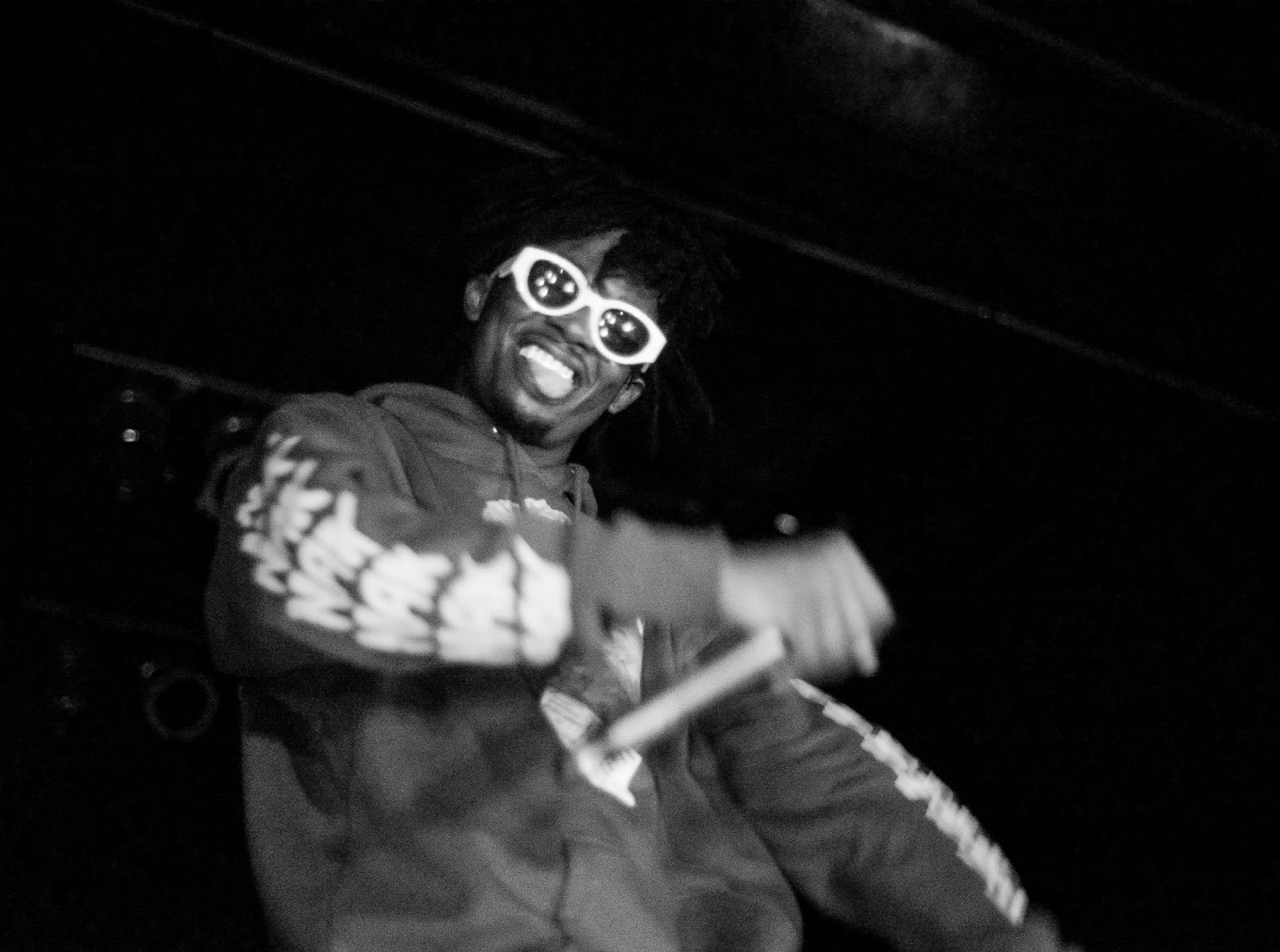 Playboi Carti wearing white sunglasses while performing on stage