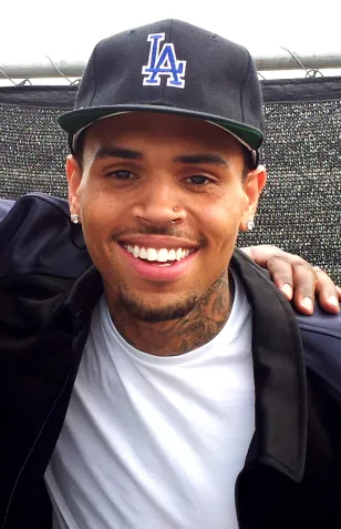 Chris Brown smiling at the BET Awards in 2013, wearing a black LA cap and white T-shirt