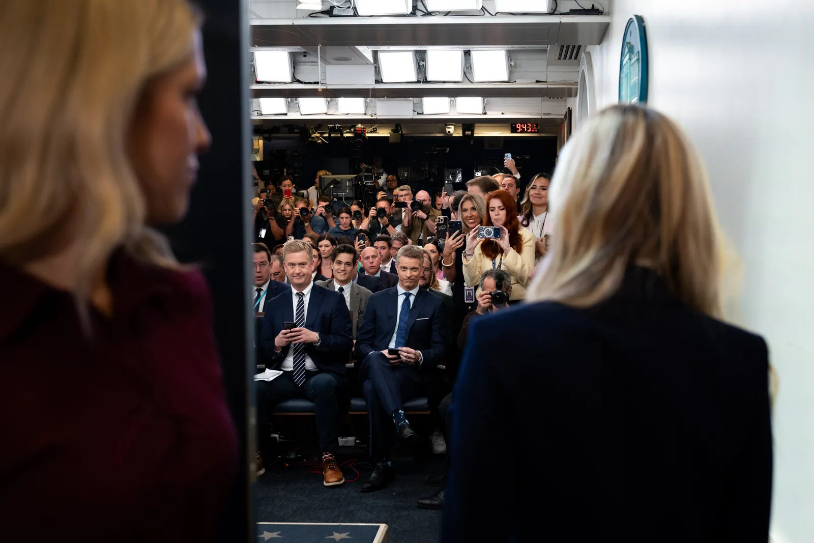 Katie Zacharia approaches the podium as reporters photograph her first White House briefing