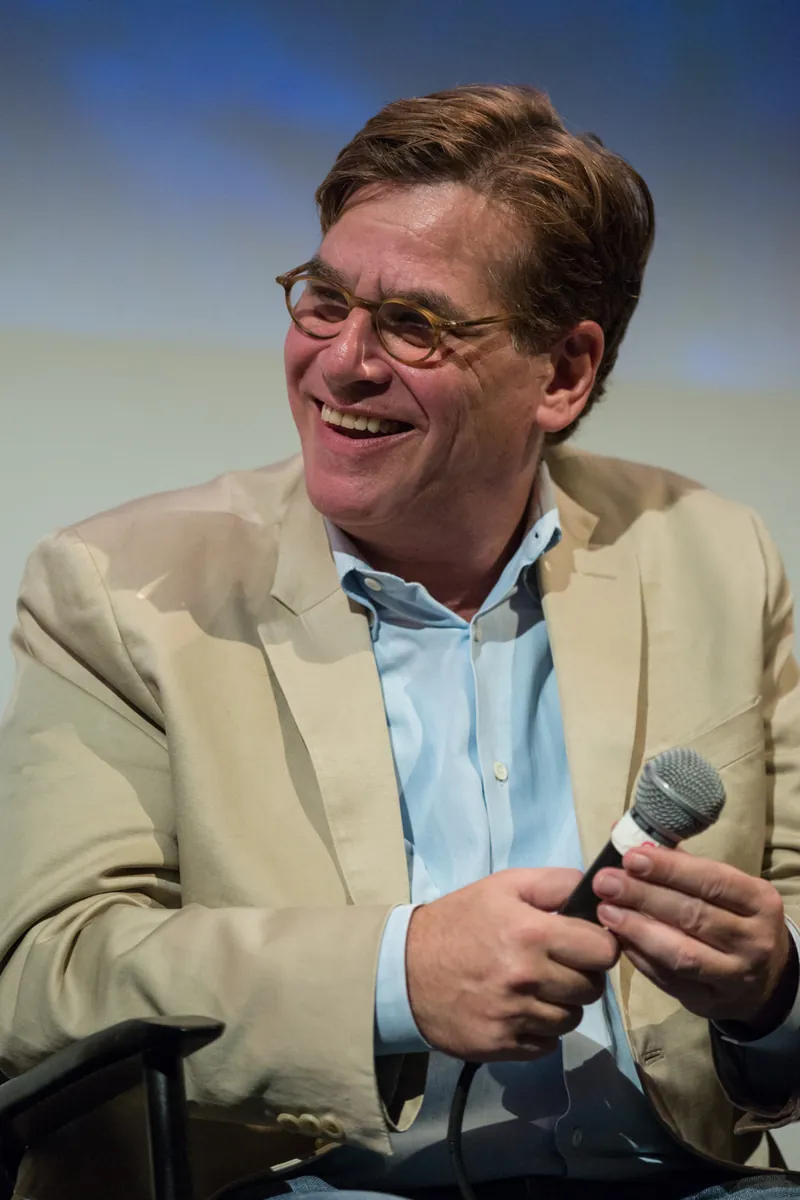 Aaron Sorkin speaks into a microphone at a panel discussion